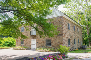 Exterior view of a 2-story stone building with a white door.
