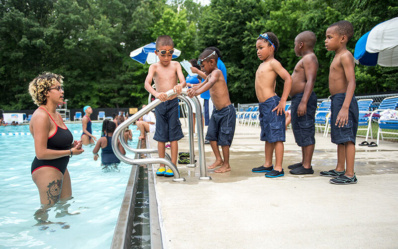 Five kids and a swimming teacher near a pool