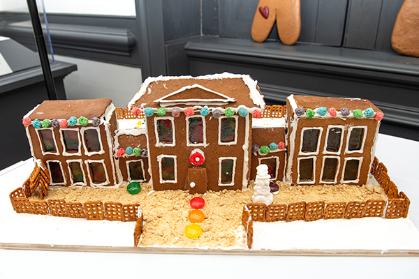 A giant two-story gingerbread house with an east and a west wing and 19 sugar pane windows on the front. A pretzel fence surrounds the house and the path leading to it.