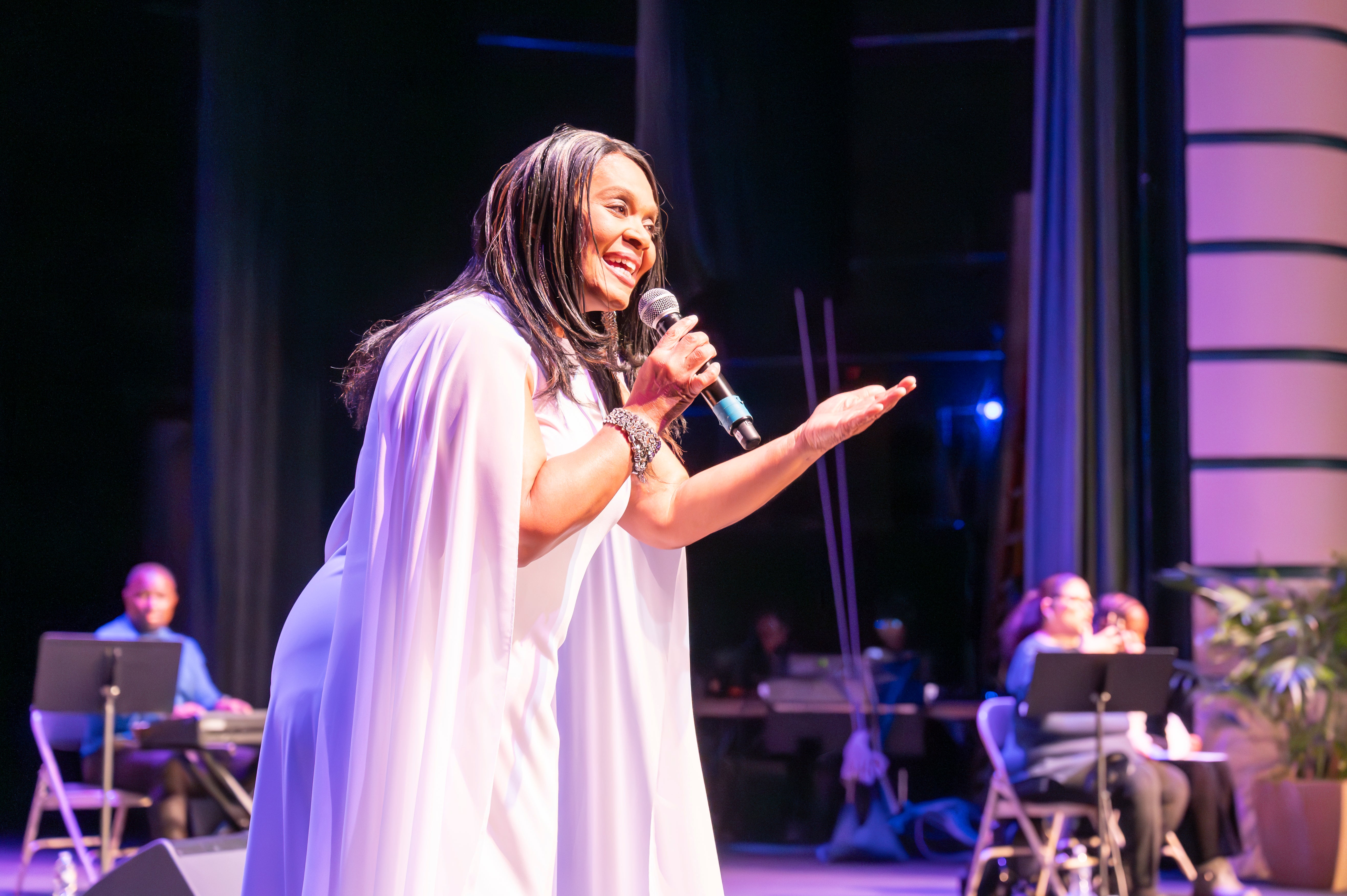 A woman on stage singing into a microphone