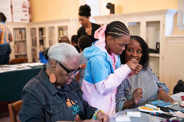 People participating in a crafts activity at a community gathering in a library-like room.