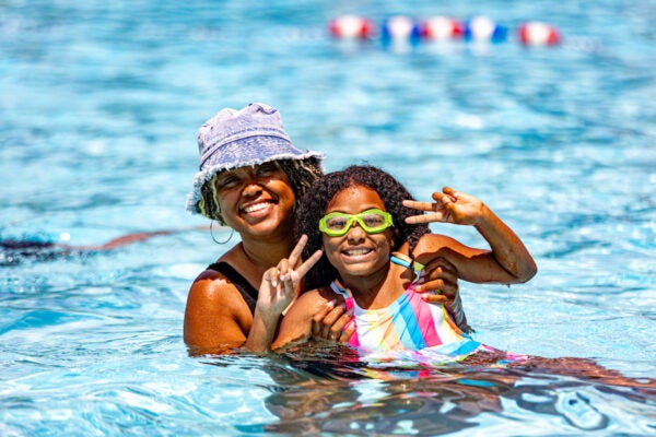 A woman holding a small girl pose for the camera in an outdoor pool.