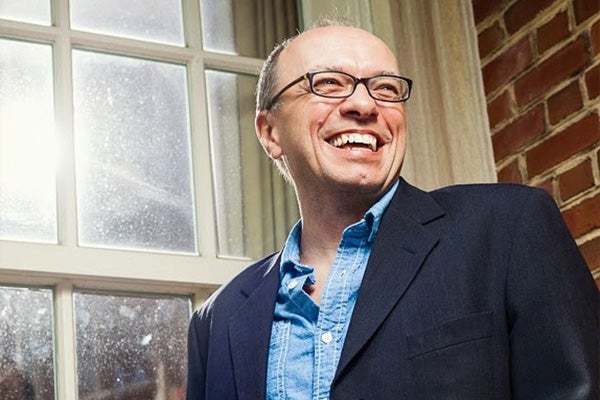 Headshot of a smiling man in a dark jacket and glasses.