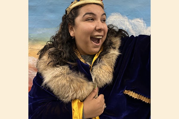A performer wears an elaborate, velvet cloak with a fur collar.