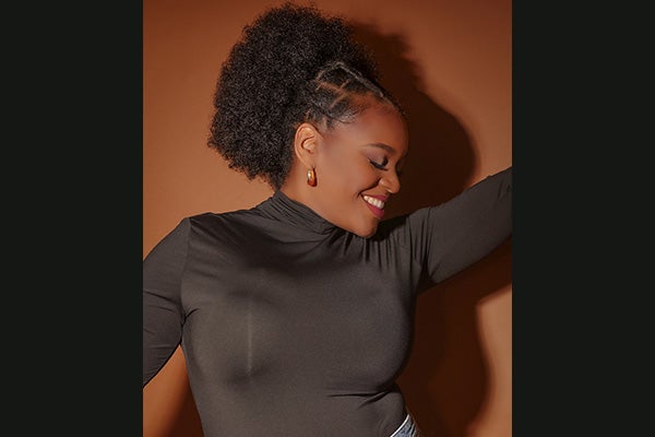 Promotional headshot of a smiling woman in a black shirt with her eyes closed.