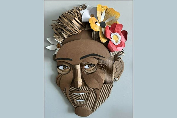 Cardboard and paper 3-D artwork depicting a smiling person with flowers in their hair.