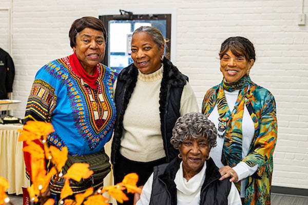 Several smiling seniors pose near a table decorated with autumn leaves.
